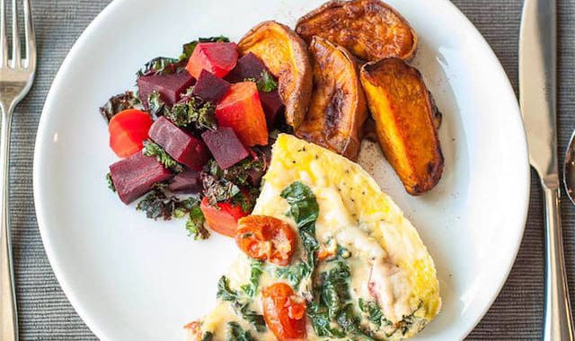 Fresh vegetable salad, roasted plantains, and cheesy spinach quiche on a white plate at Bali Stay resort.