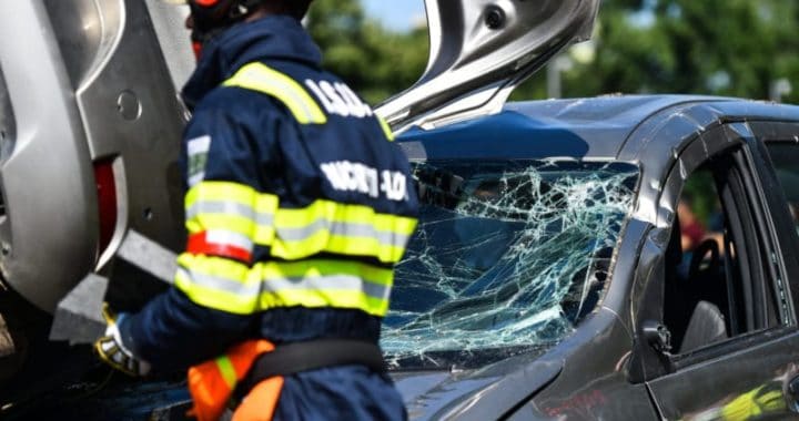Emergency rescue at traffic accident scene involving a firefighter and a damaged vehicle in Bali.