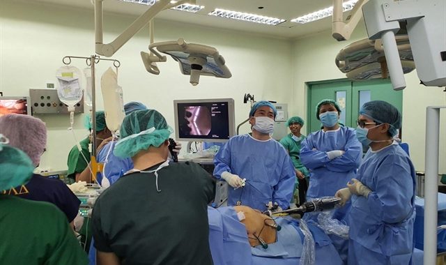 Minimally invasive surgery demonstration in a modern operating room with medical professionals.
